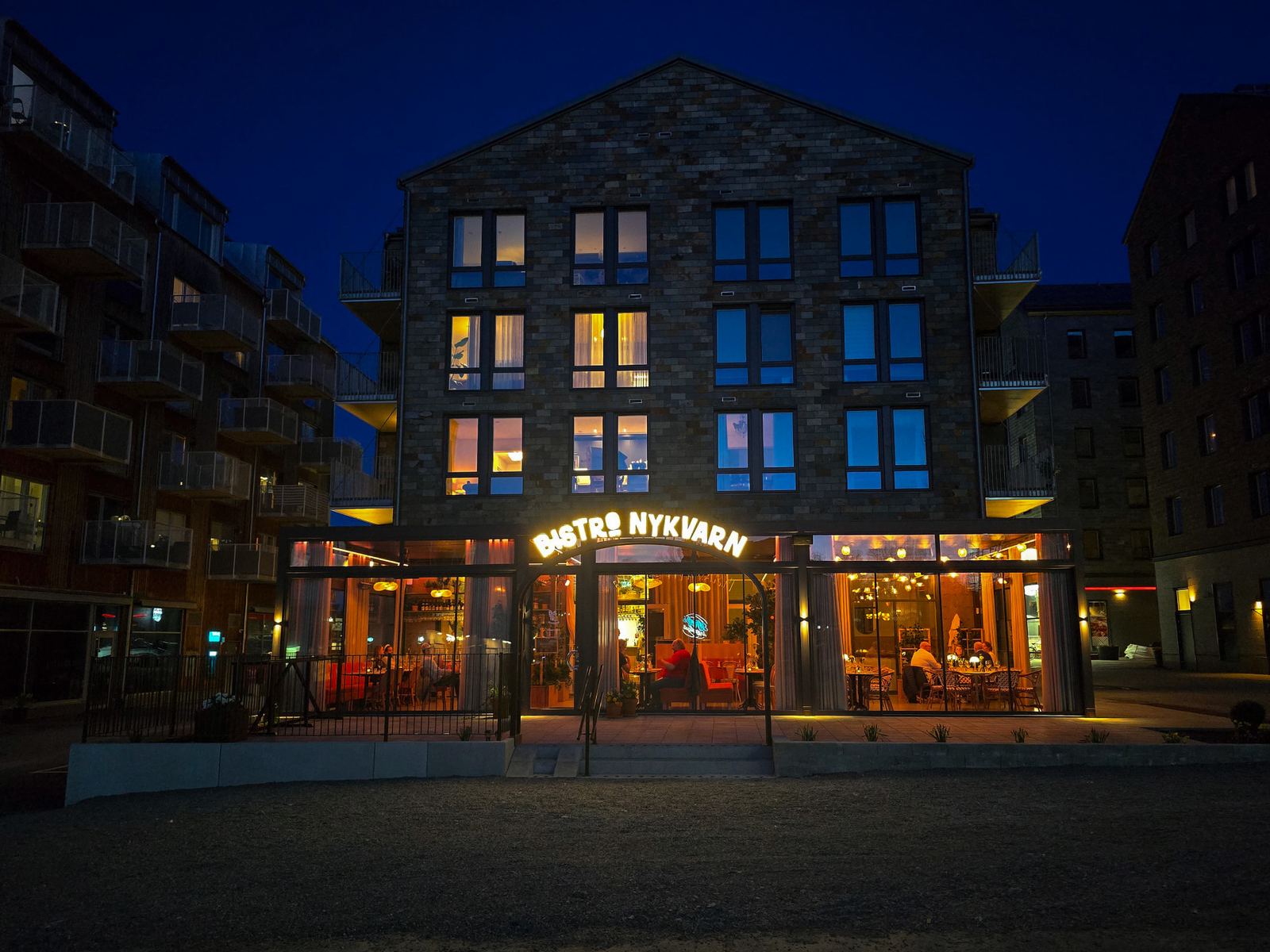 Bistro Nykvarns fasad och upplyst skylt i kvällsljus